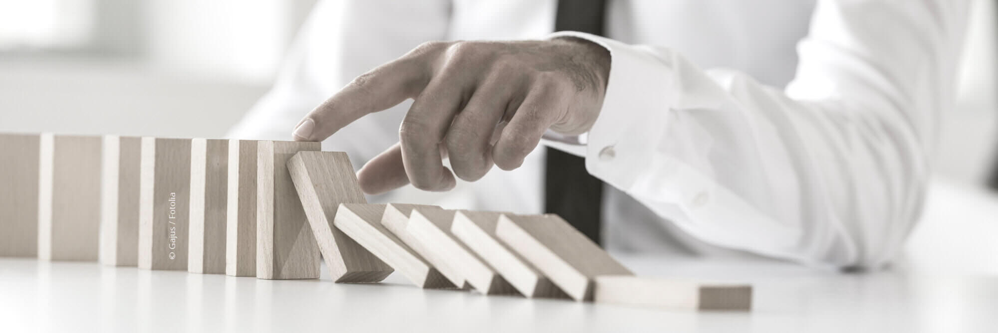 Headerfoto "Hand eines Mannes, der Dominosteine bewegt"